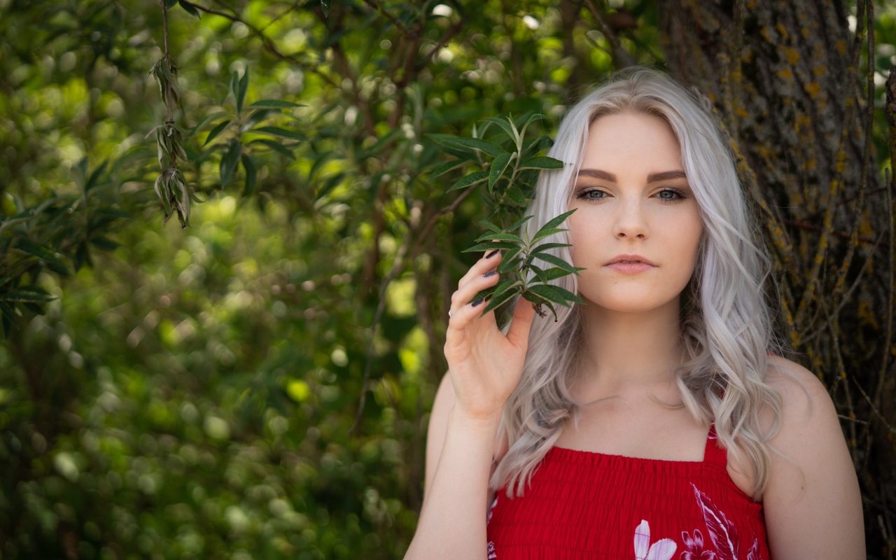 Красивая блондинка стоит у дерева 