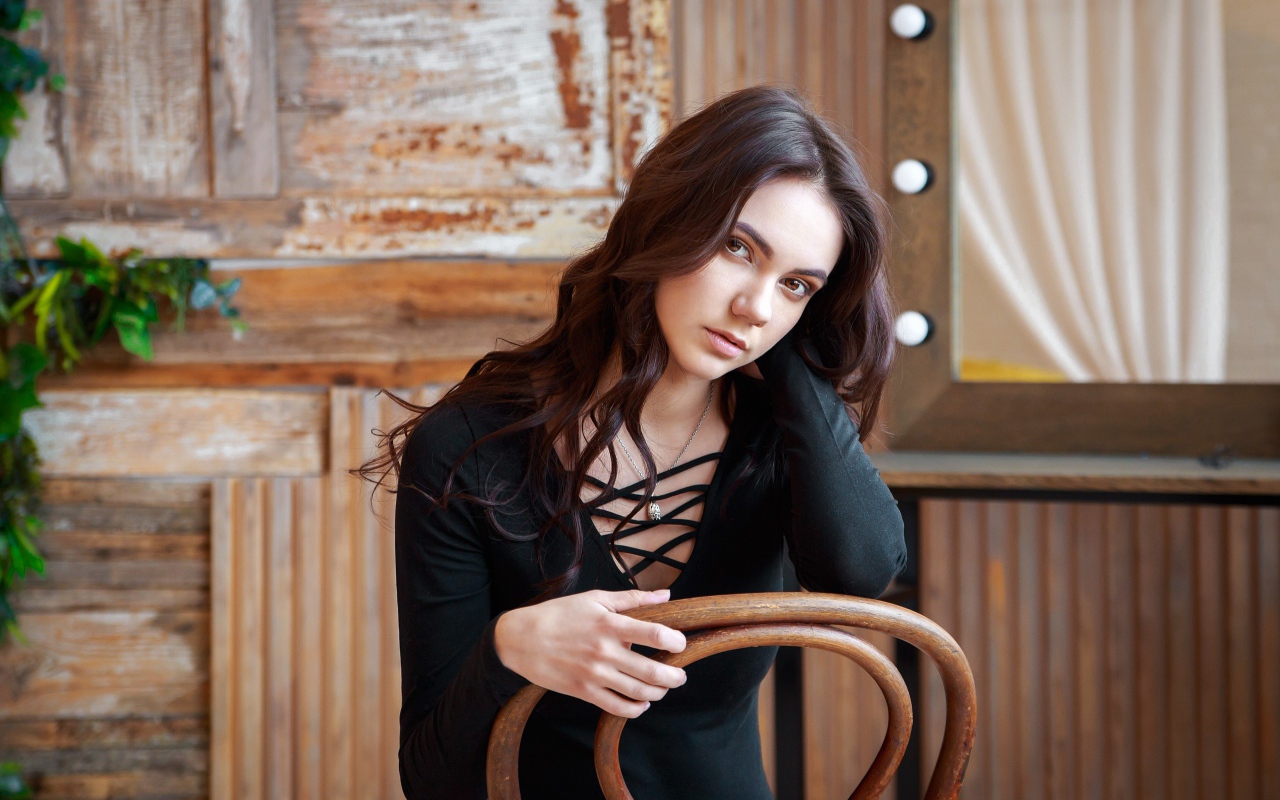 Красивая кареглазая девушка сидит на стуле