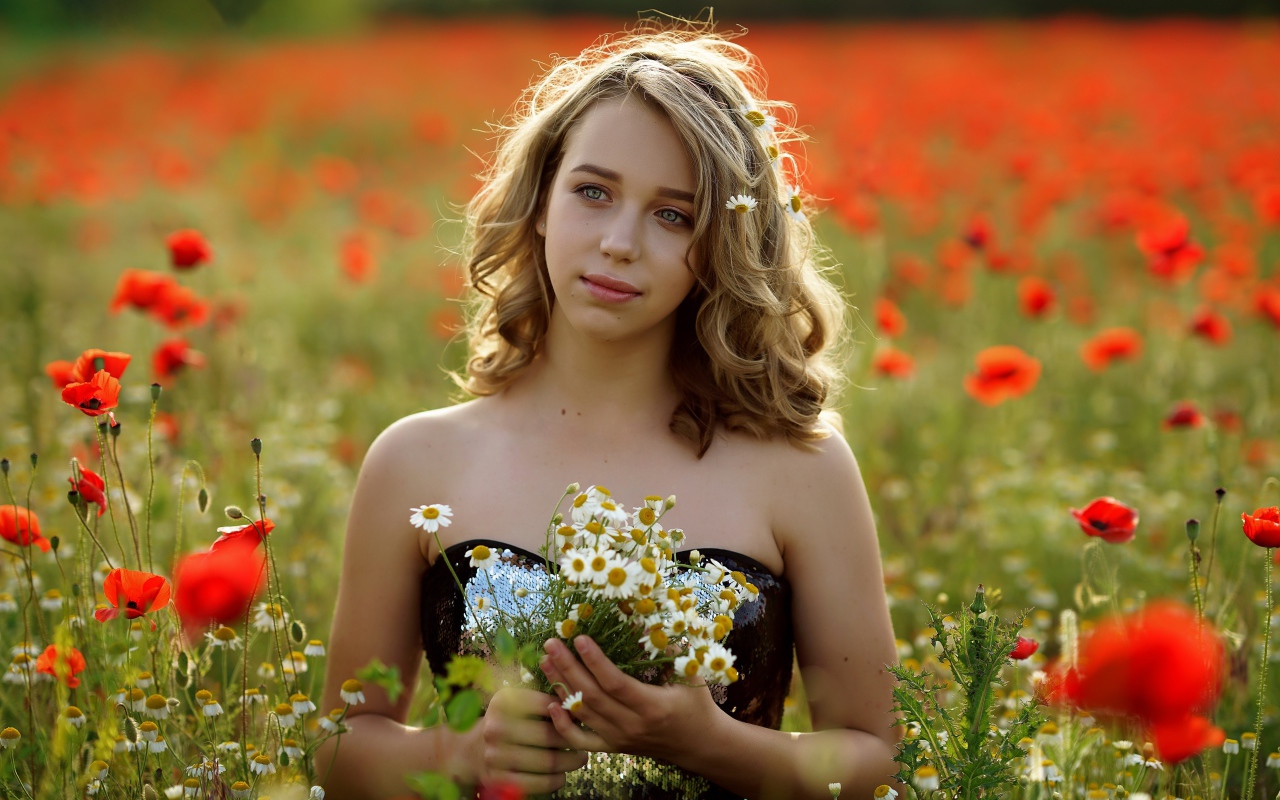 Красивая девушка с букетом ромашек на поле с маками