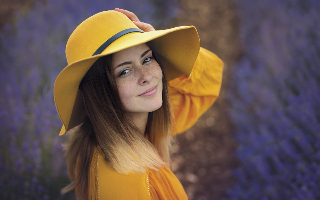 Красивая девушка с веснушками на лице в желтой шляпе