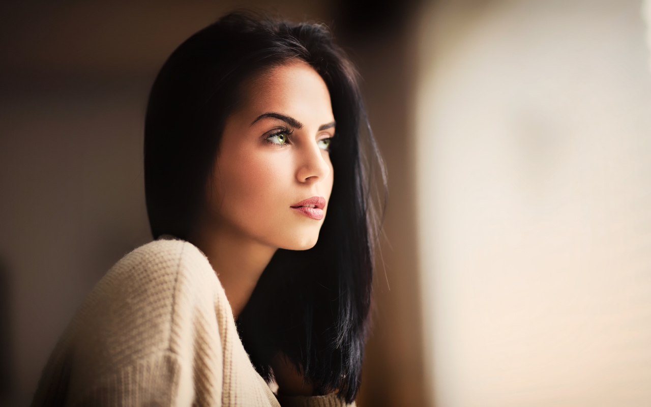 Красивая девушка зеленоглазая смотрит в окно 