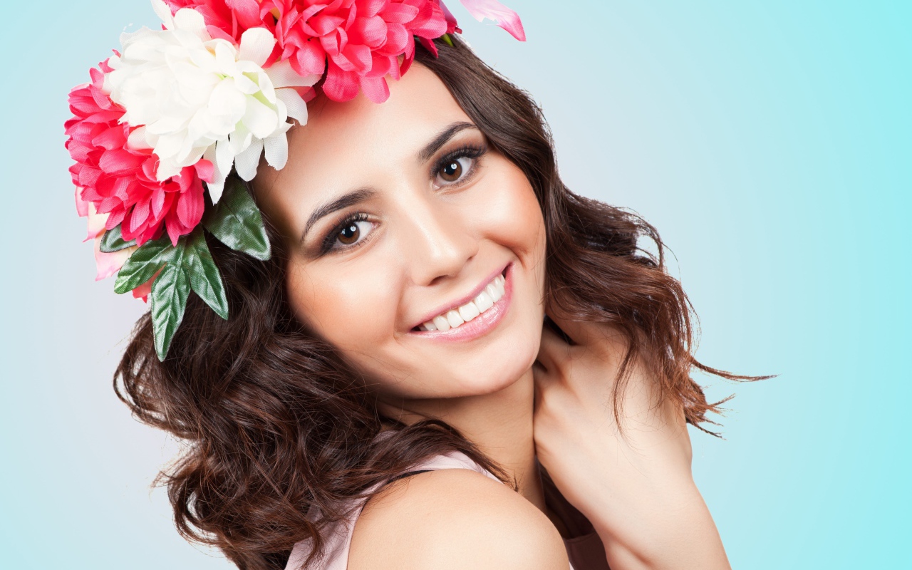 Красивая улыбающаяся девушка с венком на голове на голубом фоне