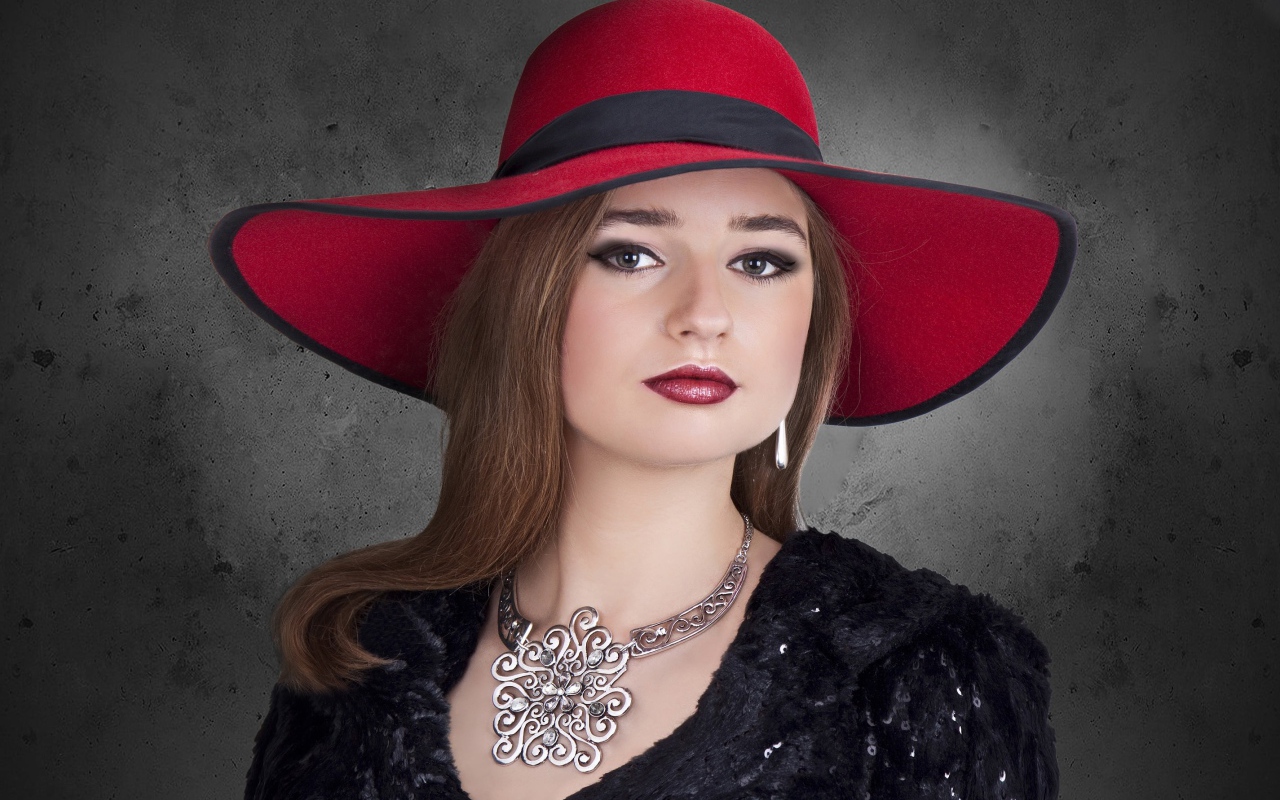Красивая стильная девушка в красной шляпе с украшением на шее 