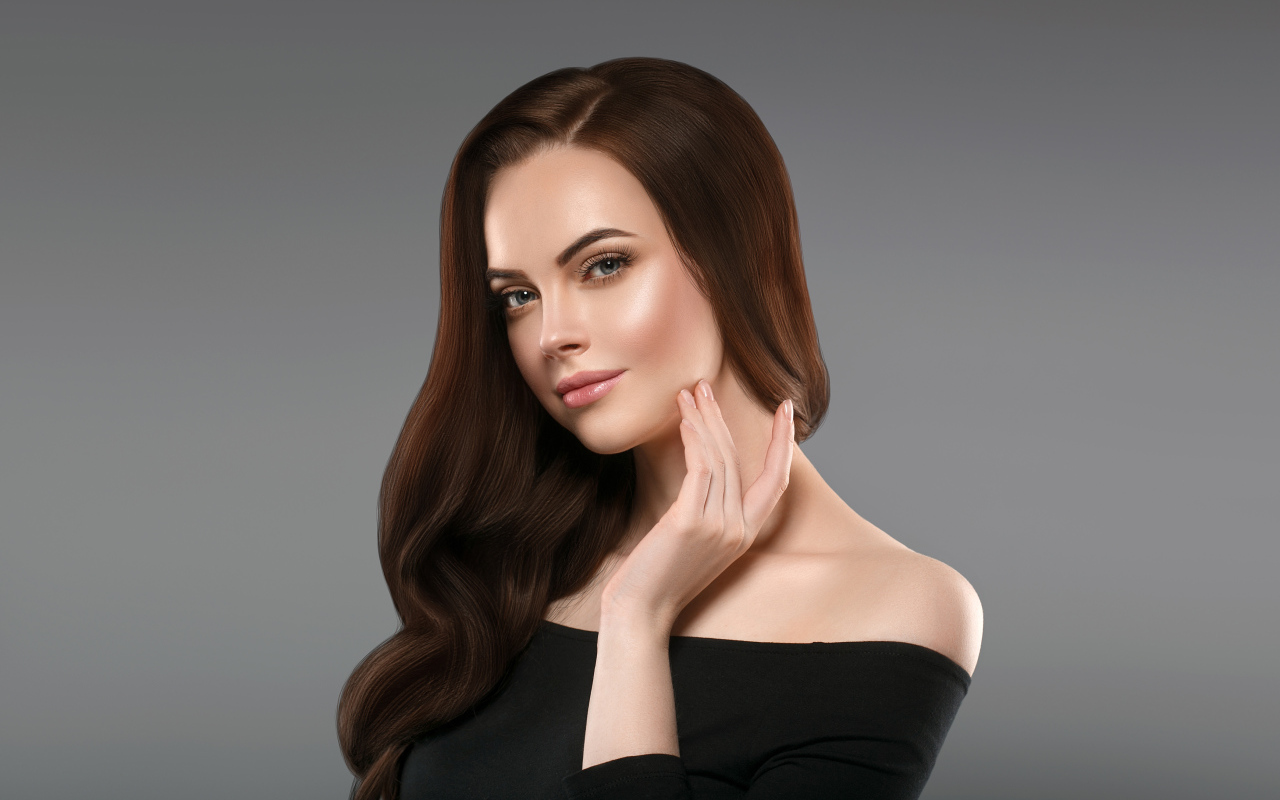 Нежная длинноволосая шатенка в черном платье на сером фоне