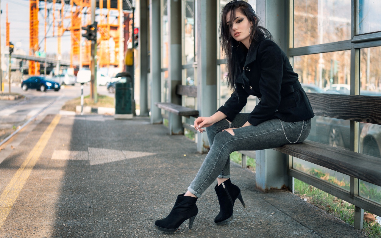 Девушка неформалка сидит на автобусной остановке
