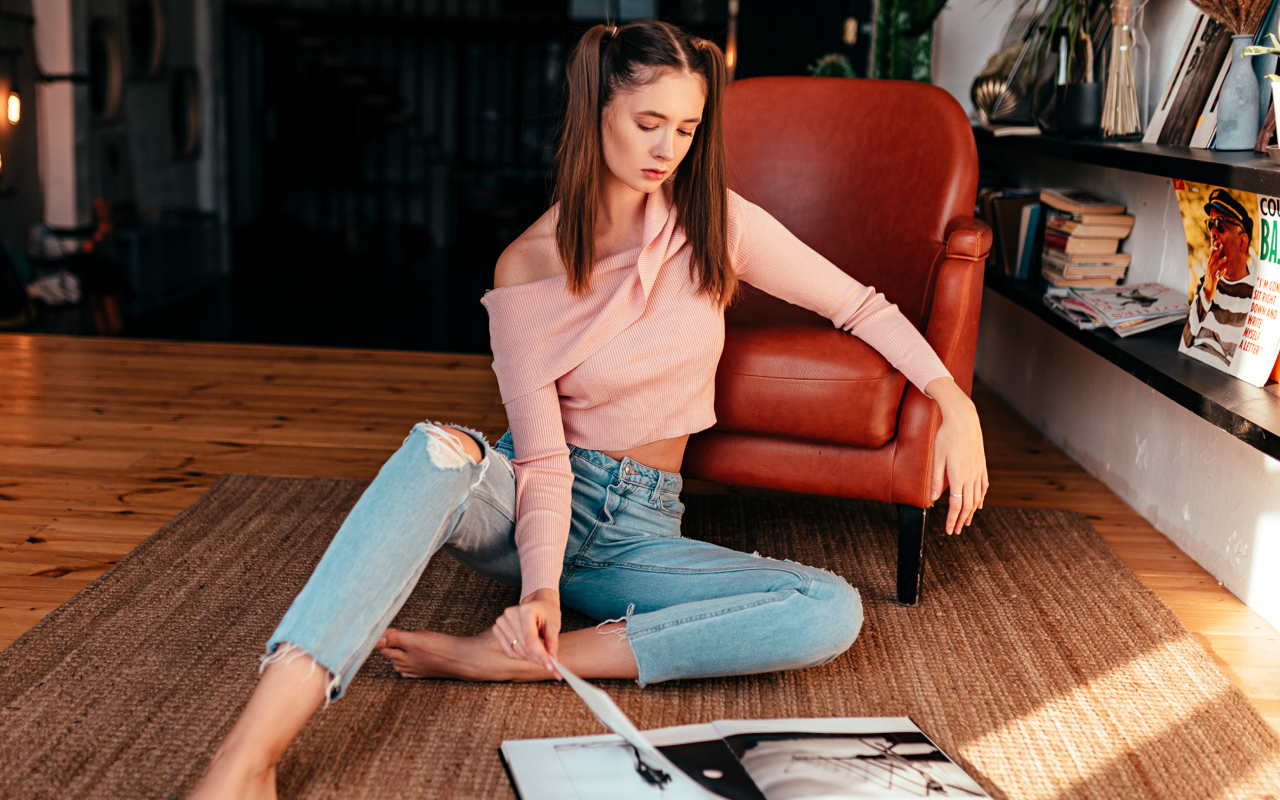 Девушка читает журнал на полу у кожаного кресла