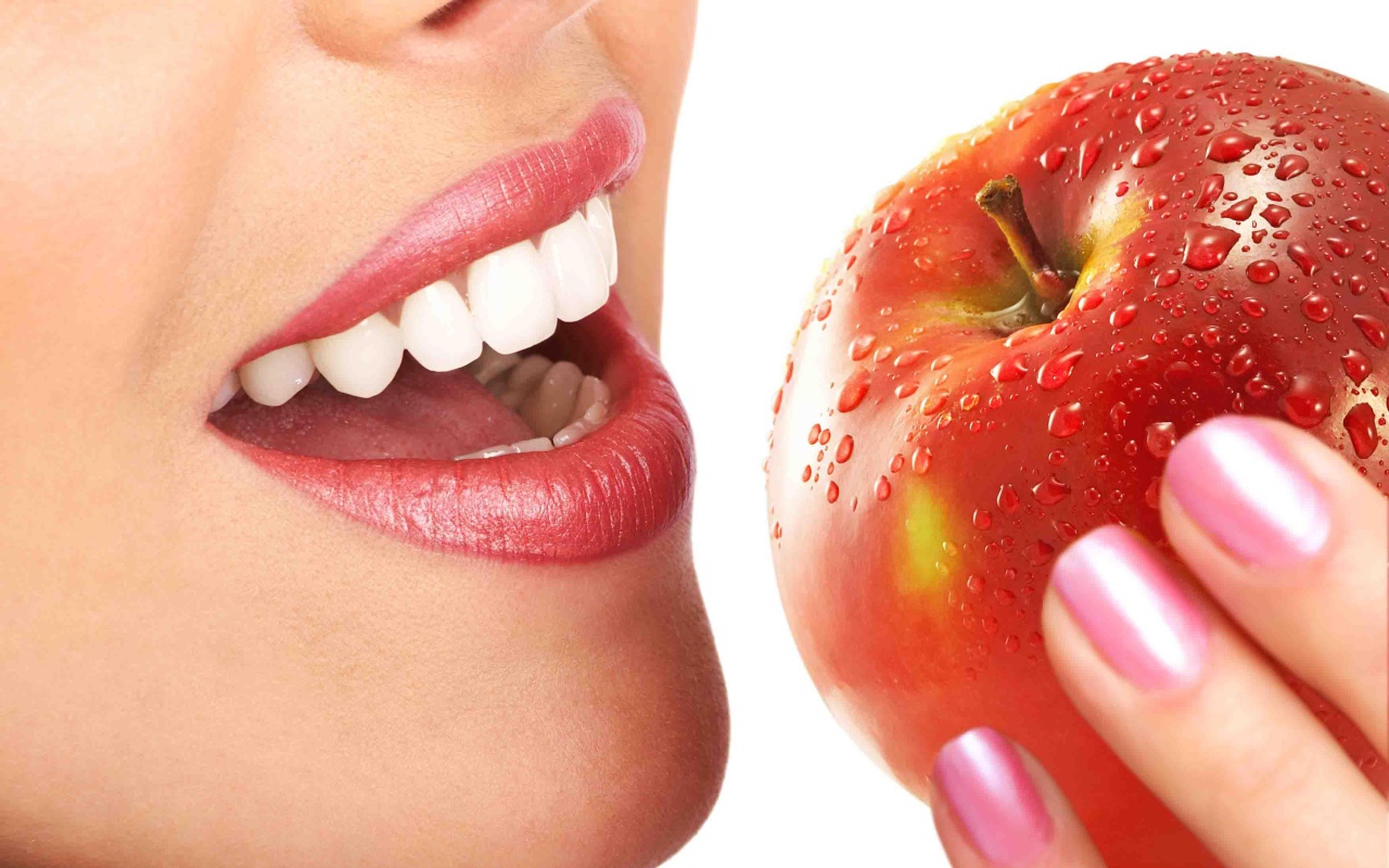 Девушка с красивыми белыми зубами кусает яблоко