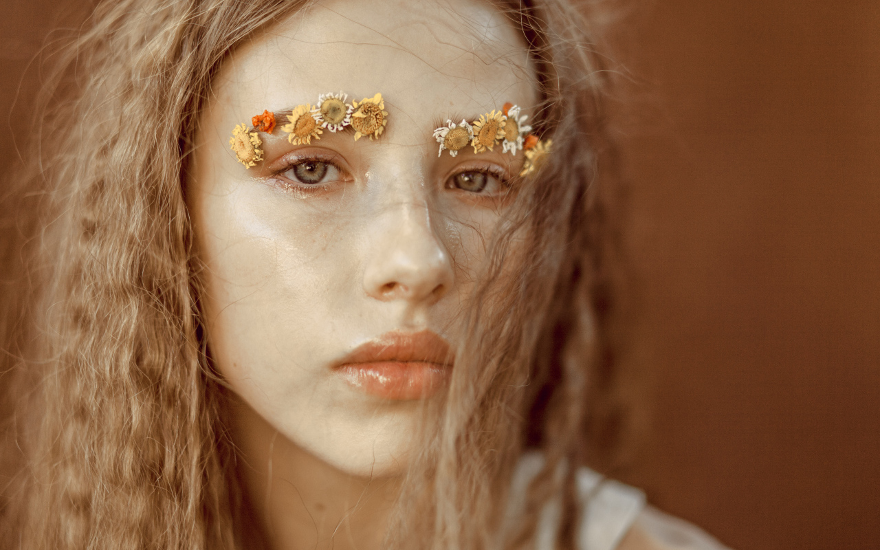 Девушка с цветами на бровях крупным планом