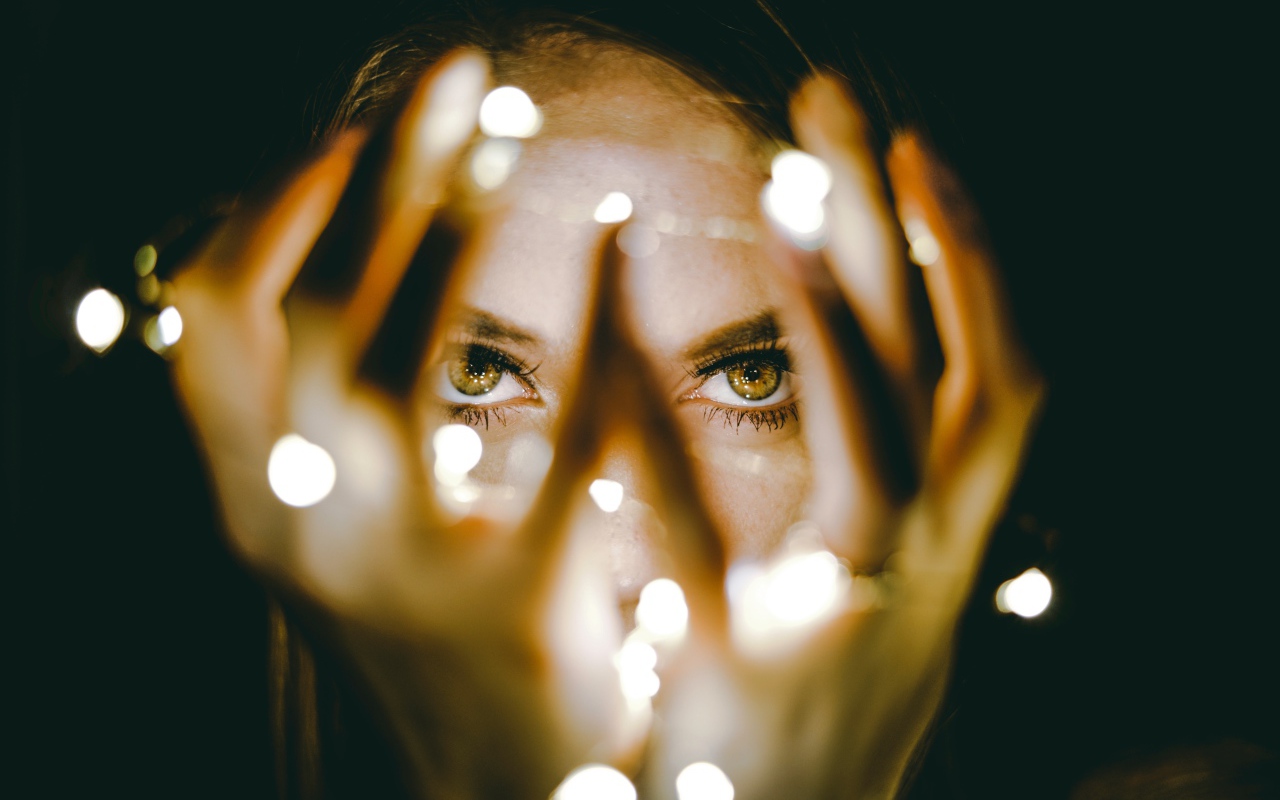 Руки с гирляндой у лица девушки