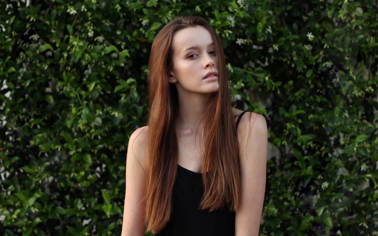 Длинноволосая шатенка на фоне зеленых зарослей