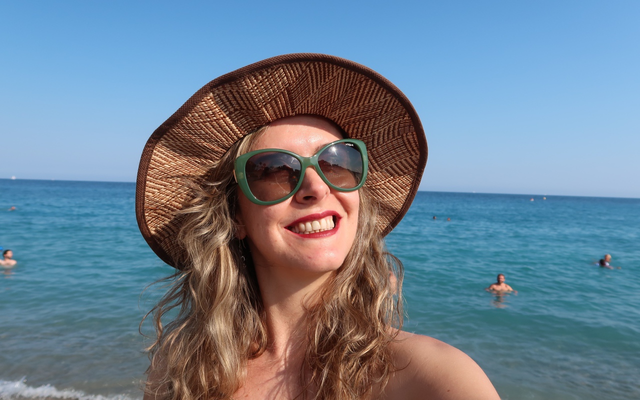 Улыбающаяся девушка в солнечных очках и шляпе на море