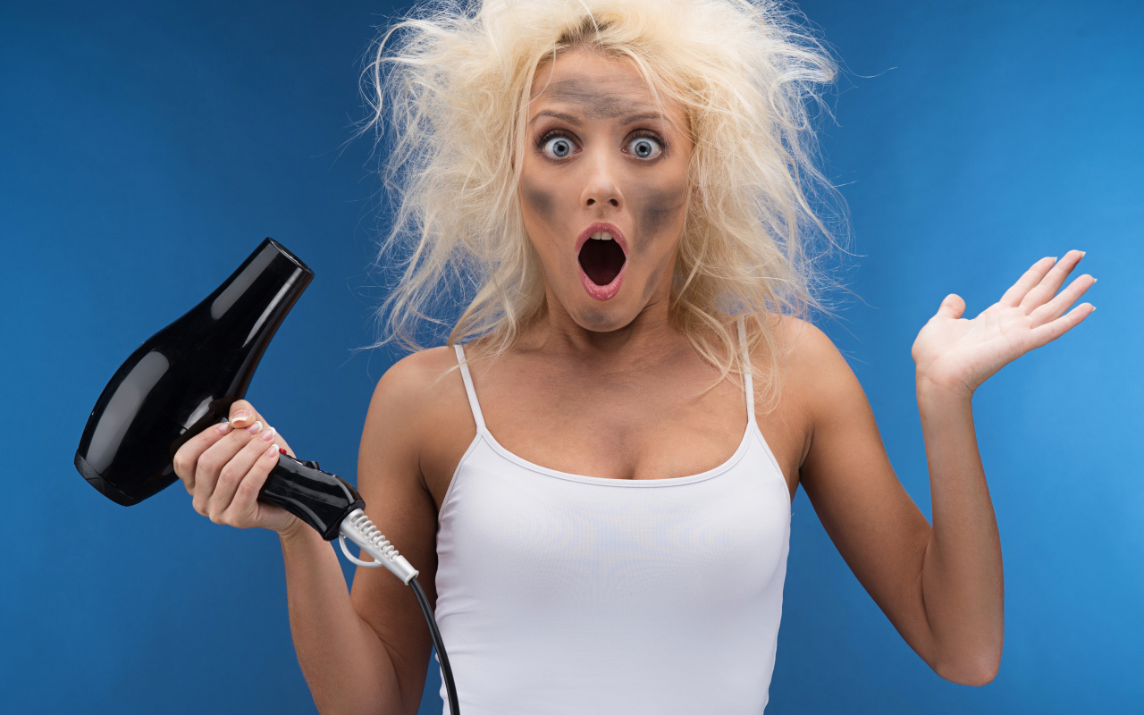 Удивленная девушка с грязным лицом с феном в руке 