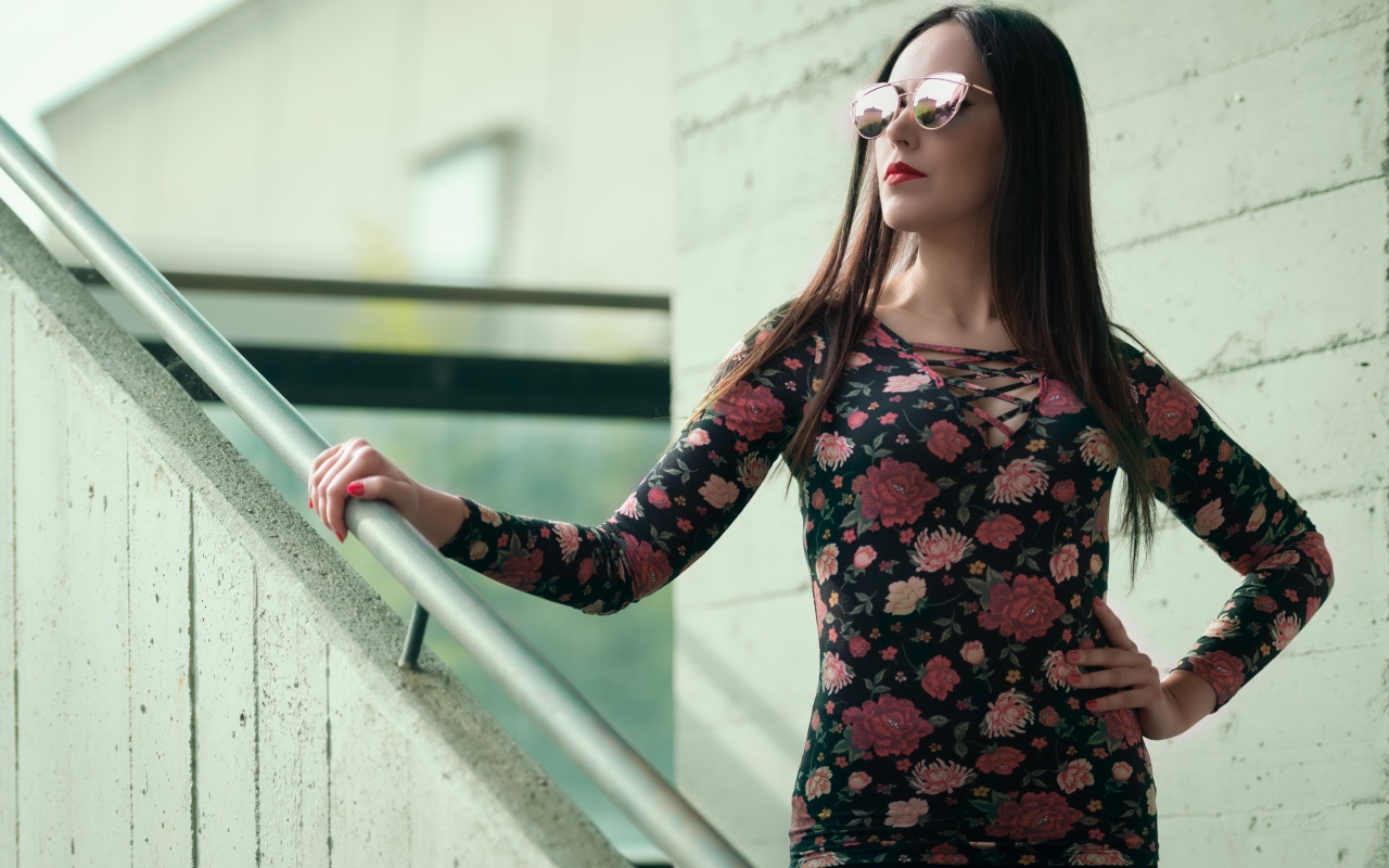 Молодая девушка в солнечных очках стоит на ступеньках