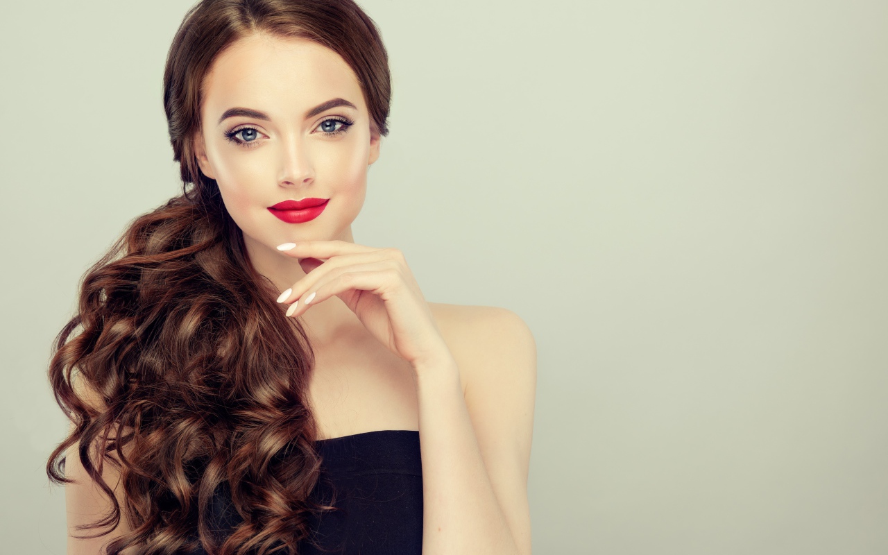 Молодая девушка с красивыми волосами на сером фоне