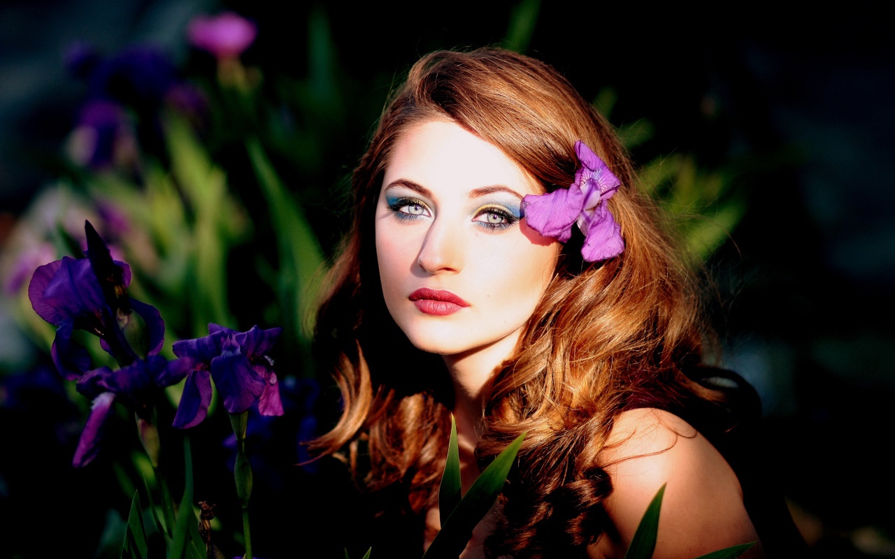 Молодая девушка с фиолетовым цветком ириса в волосах