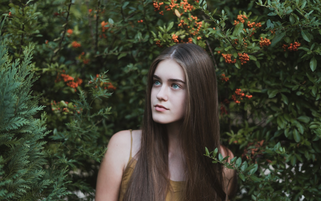 Молодая нежная девушка с длинными волосами в зеленых зарослях 