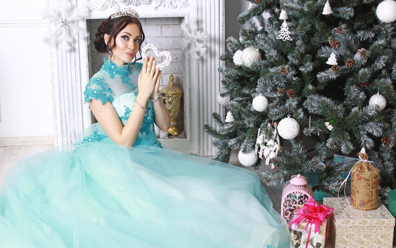 Молодая девушка в красивом голубом платье у новогодней елки