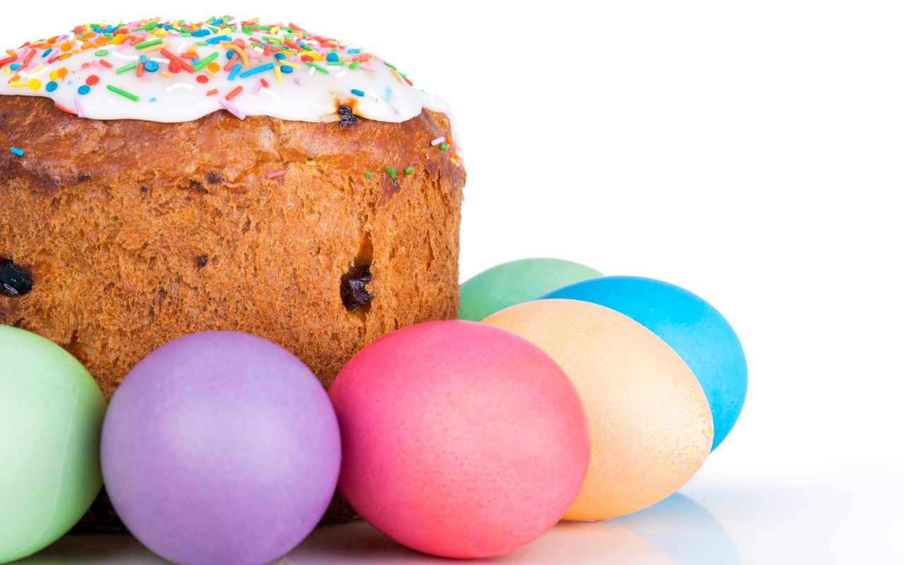 Пасхальный кулич с изюмом на белом фоне с крашеными яйцами 