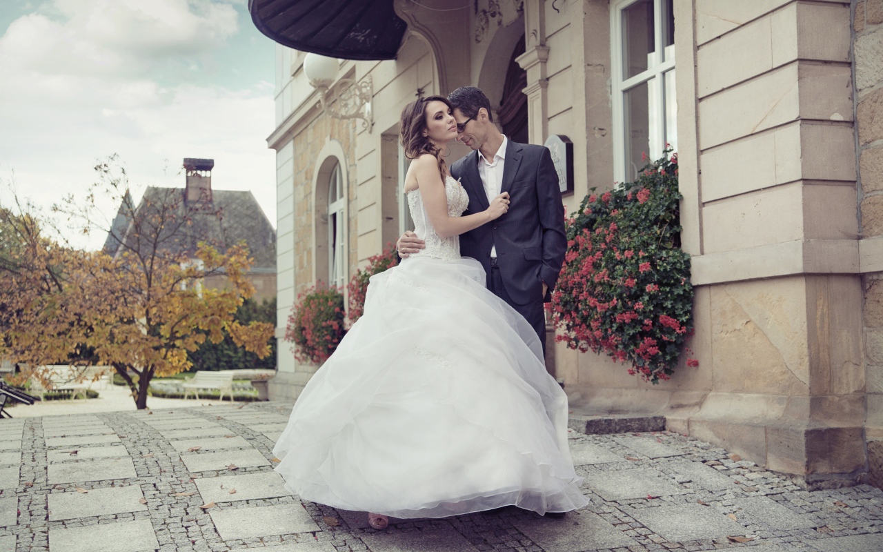 Жених и невеста стоят у здания 