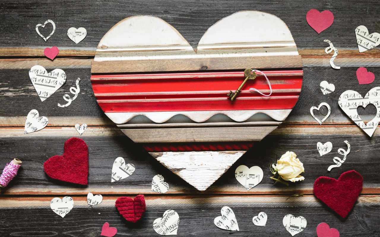 Деревянное сердце с бумажными сердечками на столе