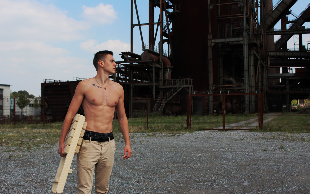 Красивый молодой парень стоит на фоне завода