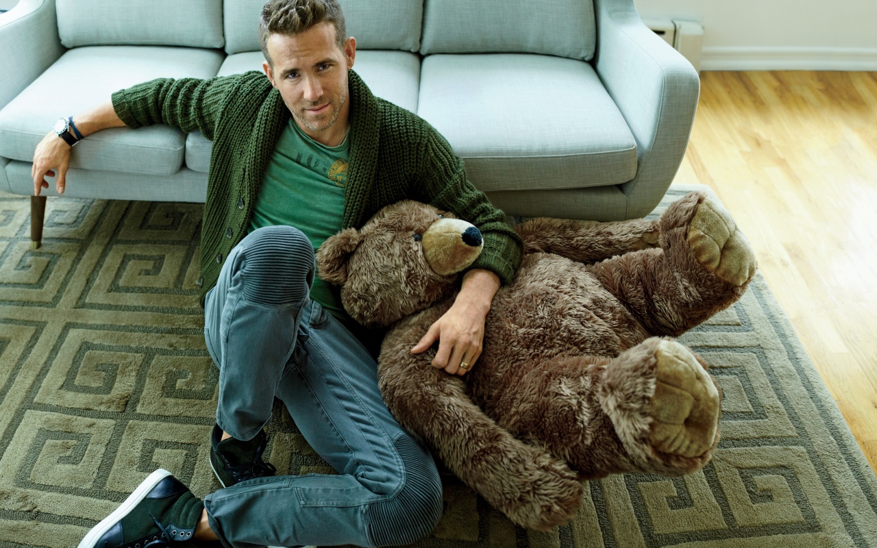 Actor Ryan Reynolds with a big teddy bear sitting on the floor