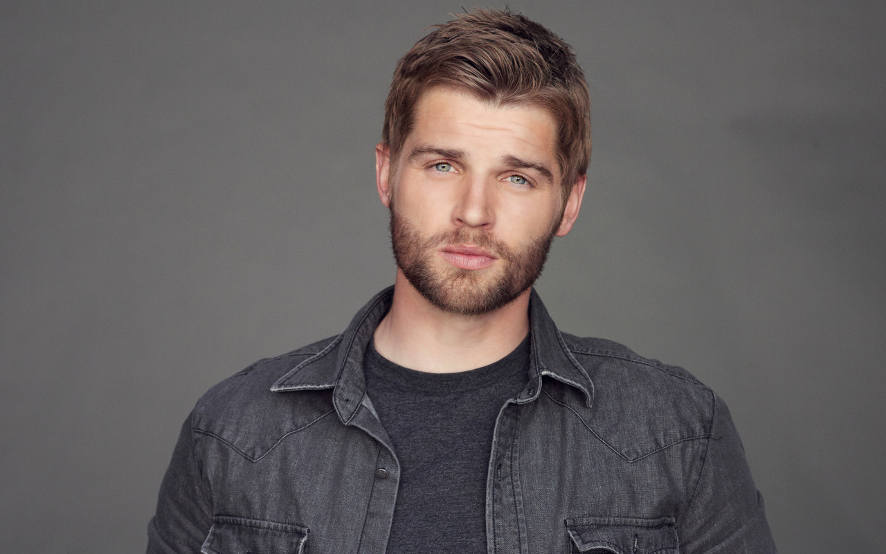 Молодой мужчина, американский актер Майкл Фогель на сером фоне