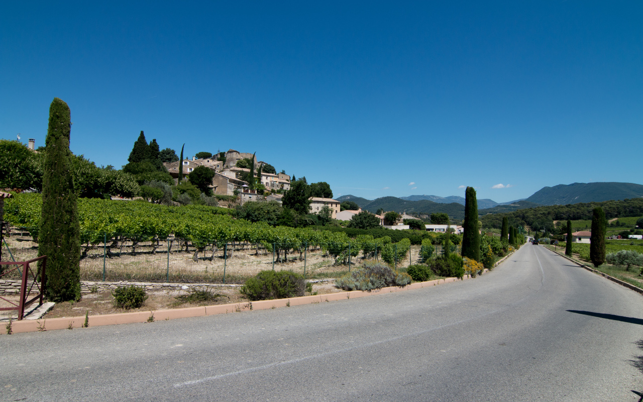 Асфальтовая дорога у большого дома под голубым небом