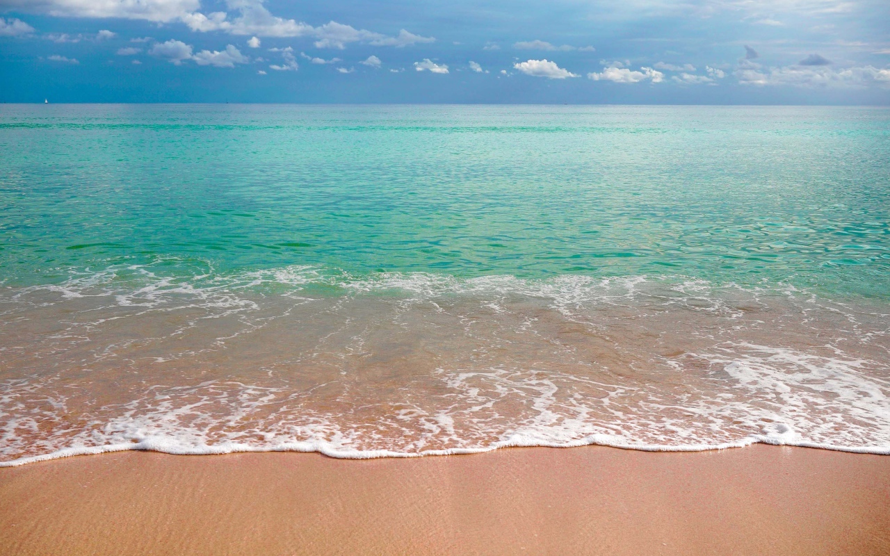 Волны голубого океана на желтом песке под голубым небом