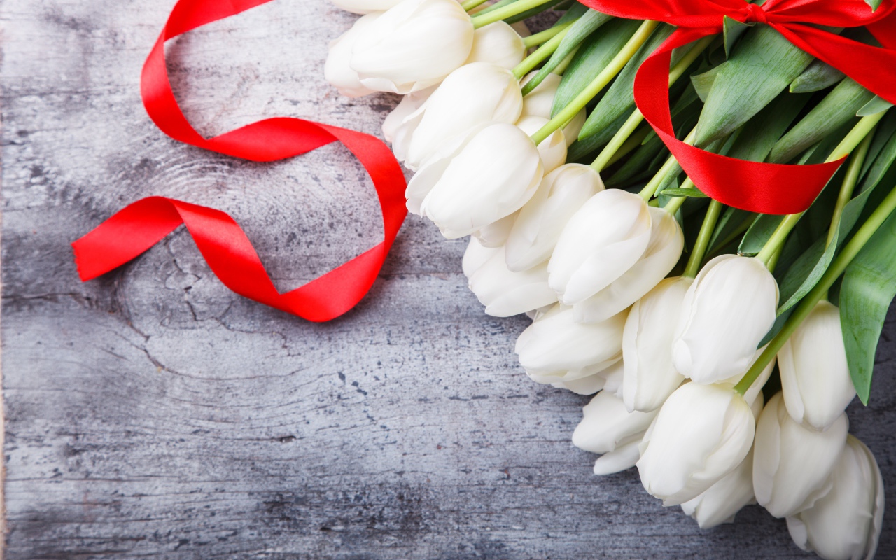 Букет белых тюльпанов с красным бантом на сером столе