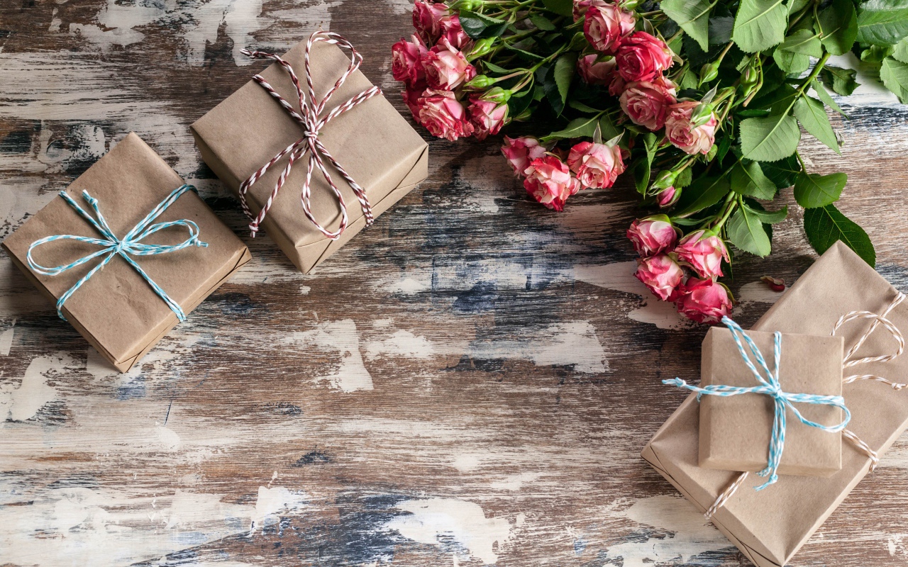 Подарочные коробки на деревянной поверхности с букетом роз