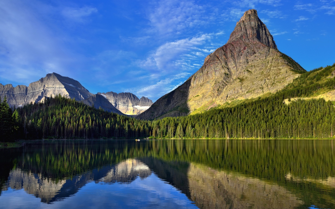 Каменные горы под голубым небом отражаются в воде