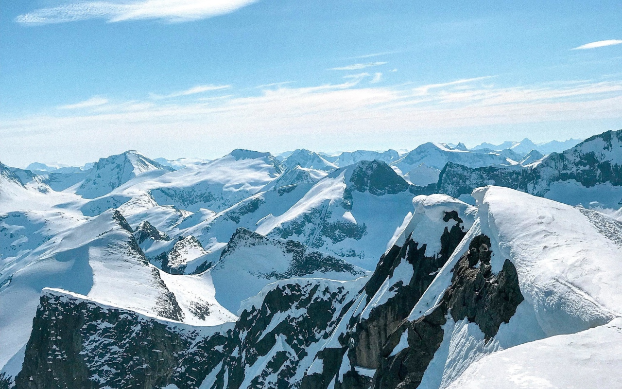Верхушки заснеженных гор в лучах солнца под голубым небом 