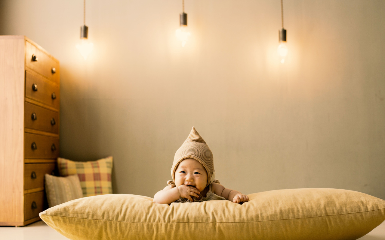 Маленький ребенок лежит на подушке под лампами