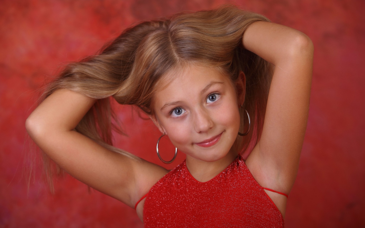 Красивая маленькая девочка с руками в волосах