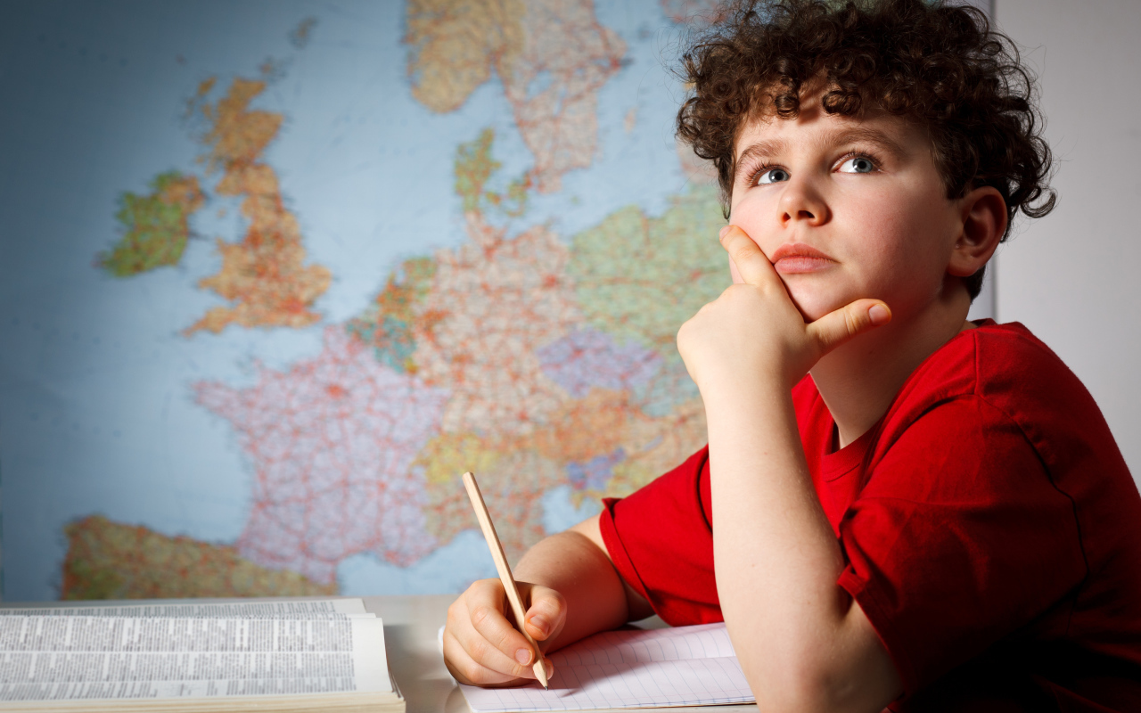 Мальчик ученик делает уроки за столом 