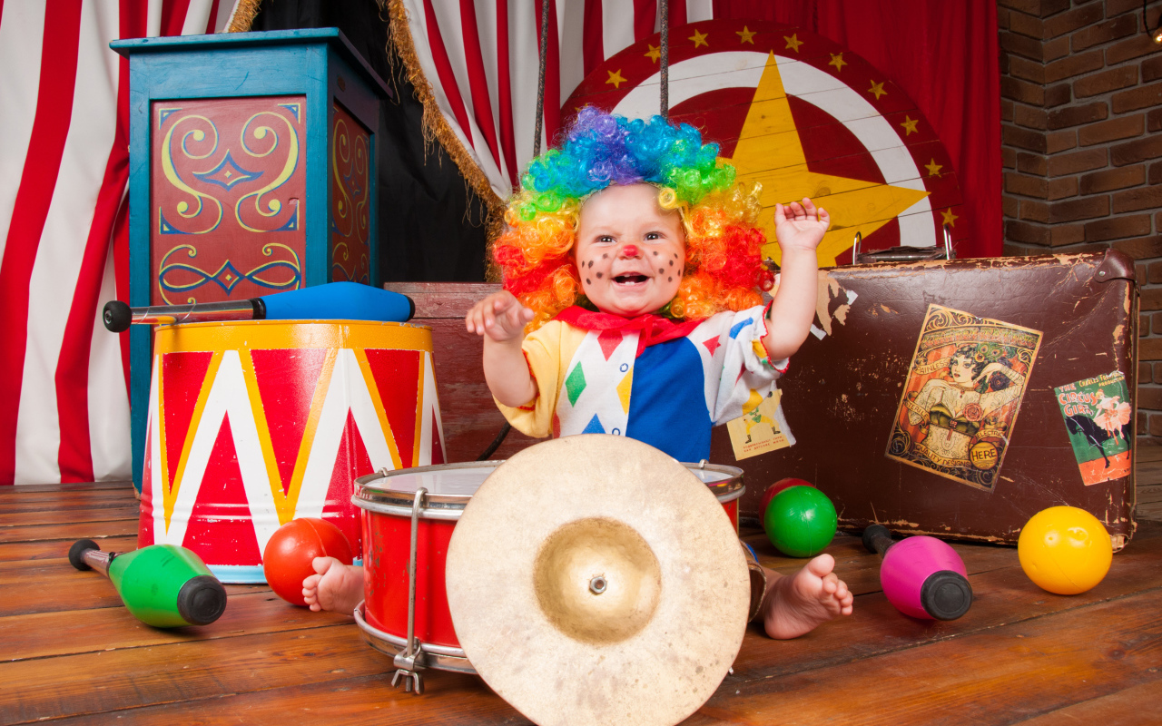 Маленький ребенок в костюме клоуна с музыкальными инструментами