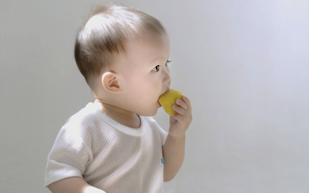 Маленький ребенок грызет игрушку на сером фоне