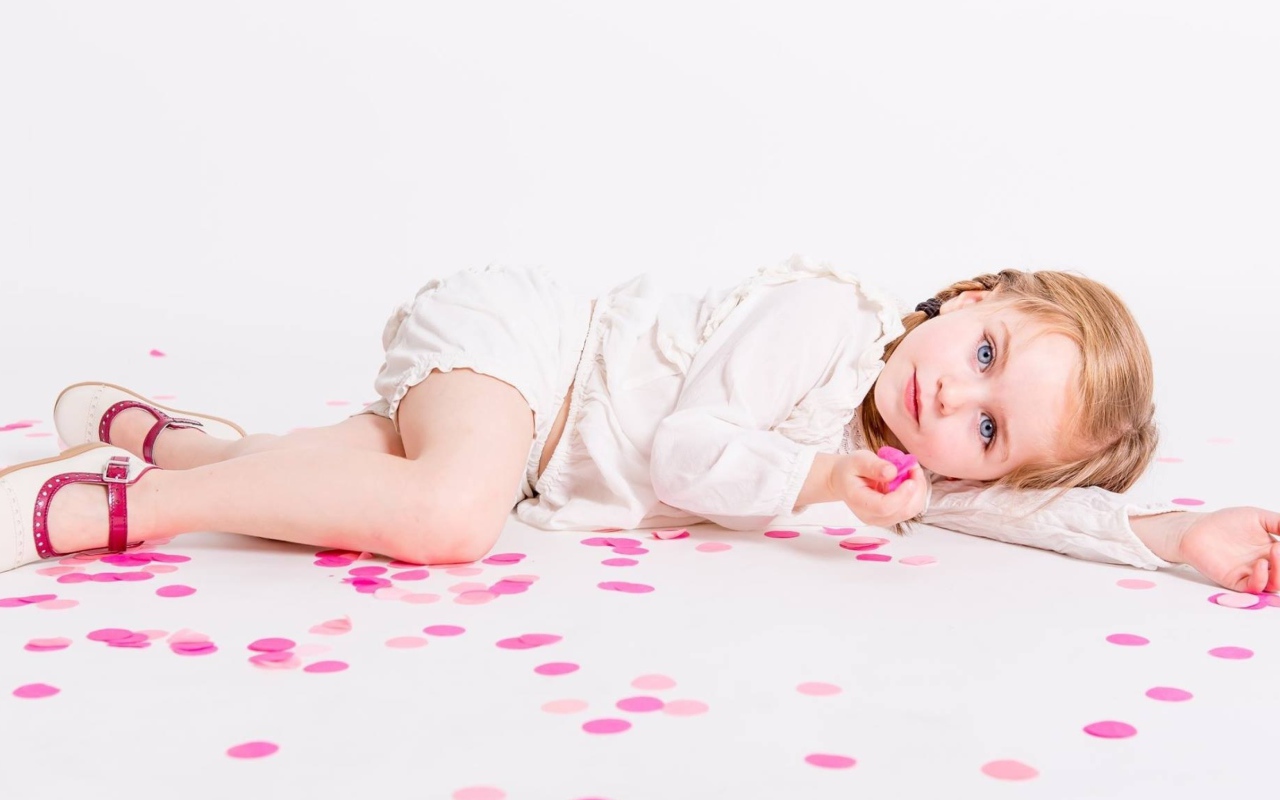 Маленькая голубоглазая девочка лежит на полу