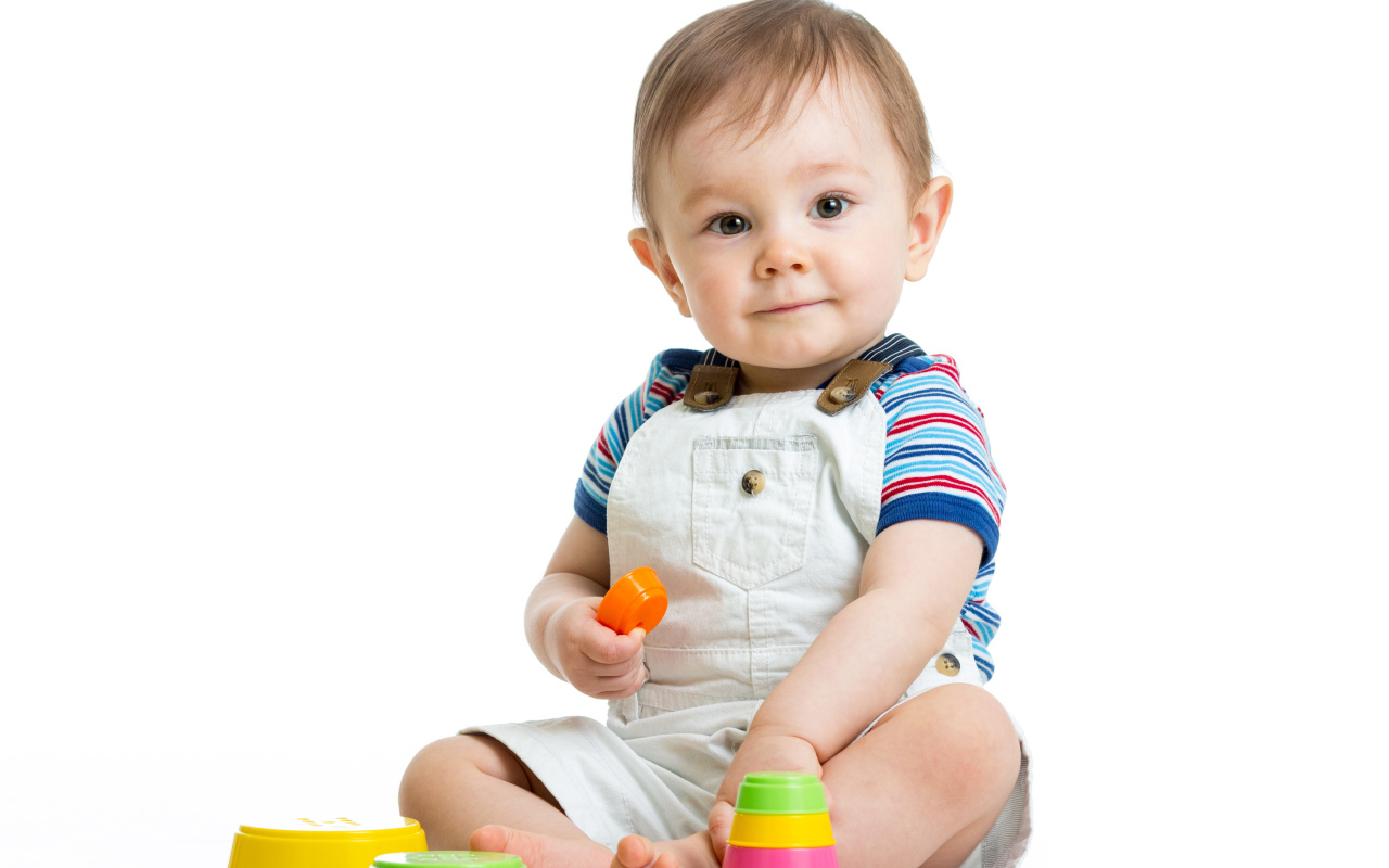 Маленький мальчик играет с пирамидкой на белом фоне