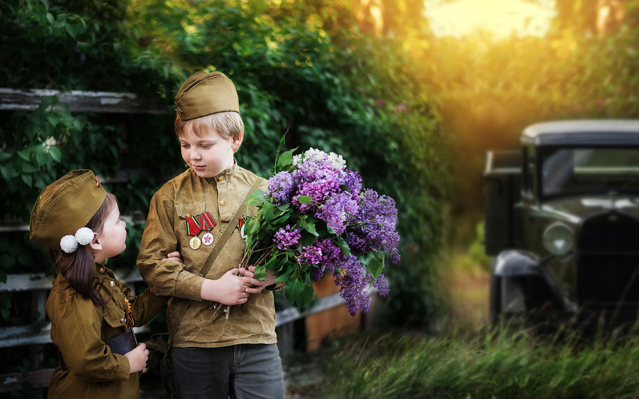 Маленький мальчик с девочкой в военной форме с букетом сирени на 9 мая 