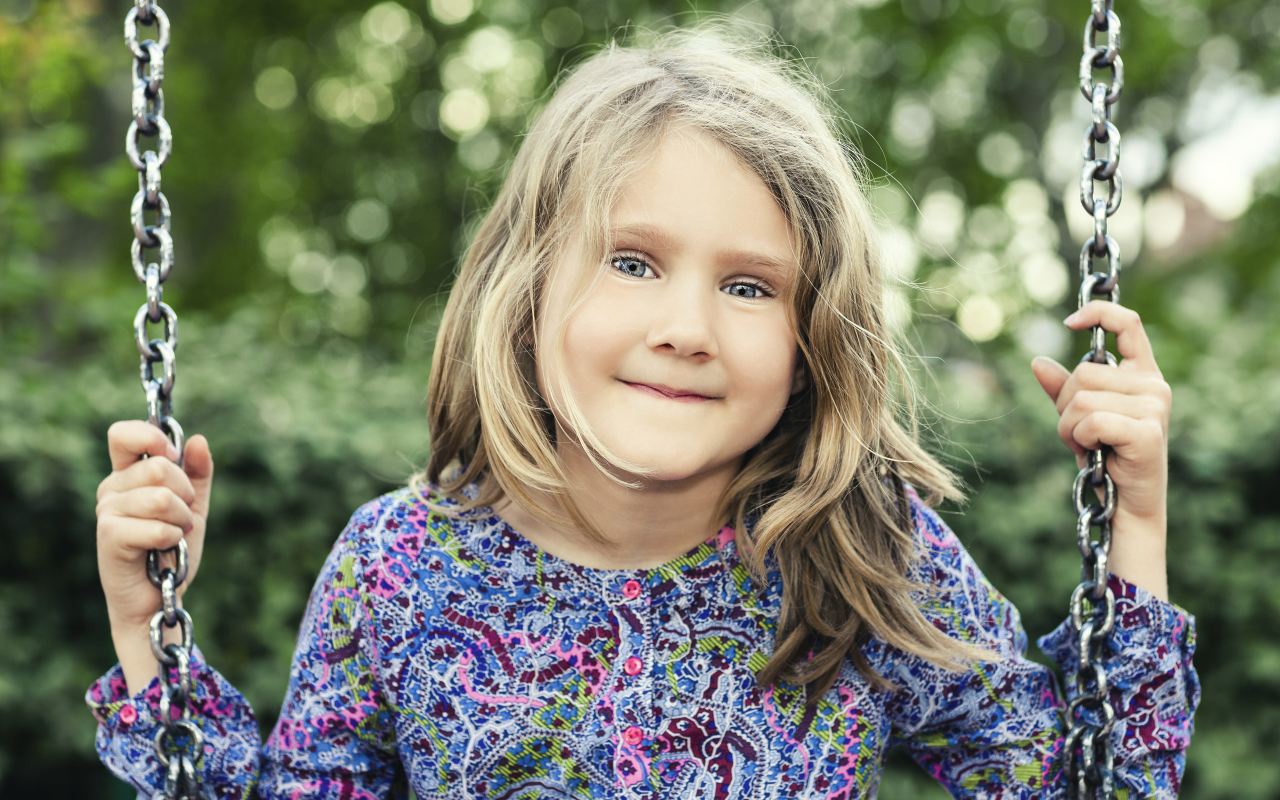 Маленькая милая голубоглазая девочка на качели