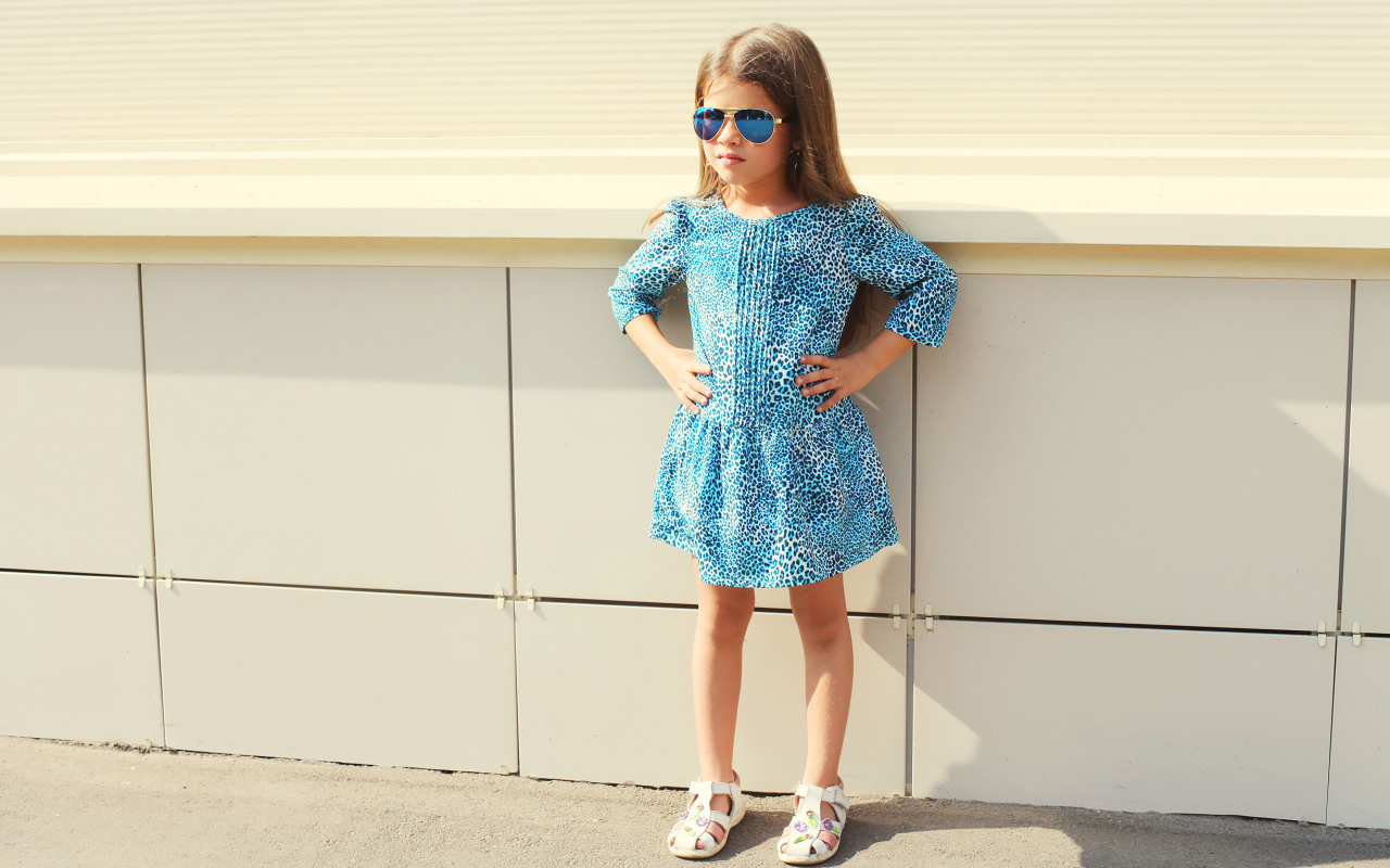 Маленькая девочка в красивом платье у стены