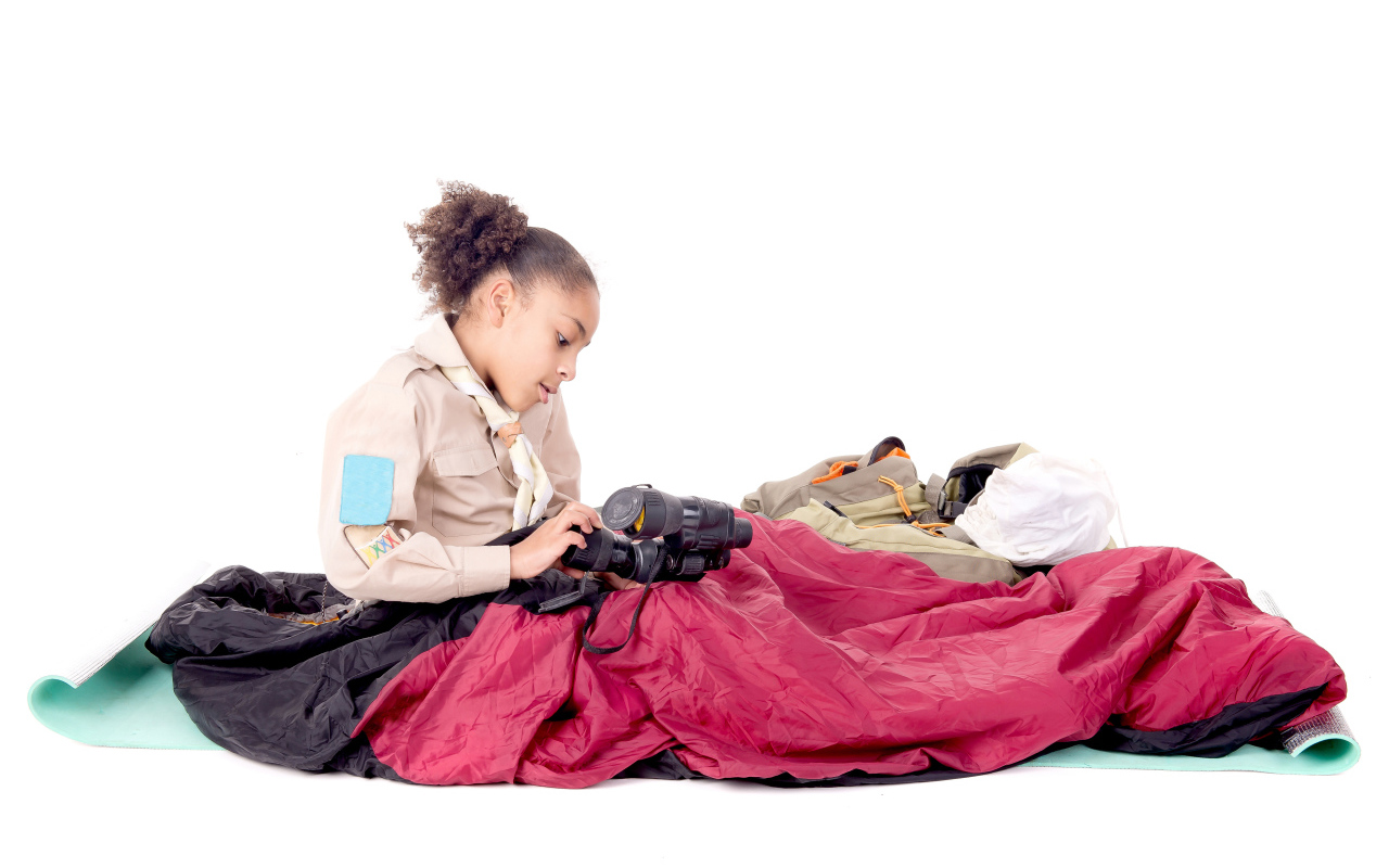 Маленькая девочка в спальном мешке с биноклем