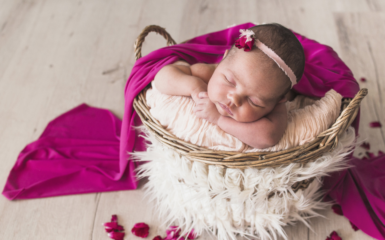 Маленькая девочка спит в корзине под покрывалом