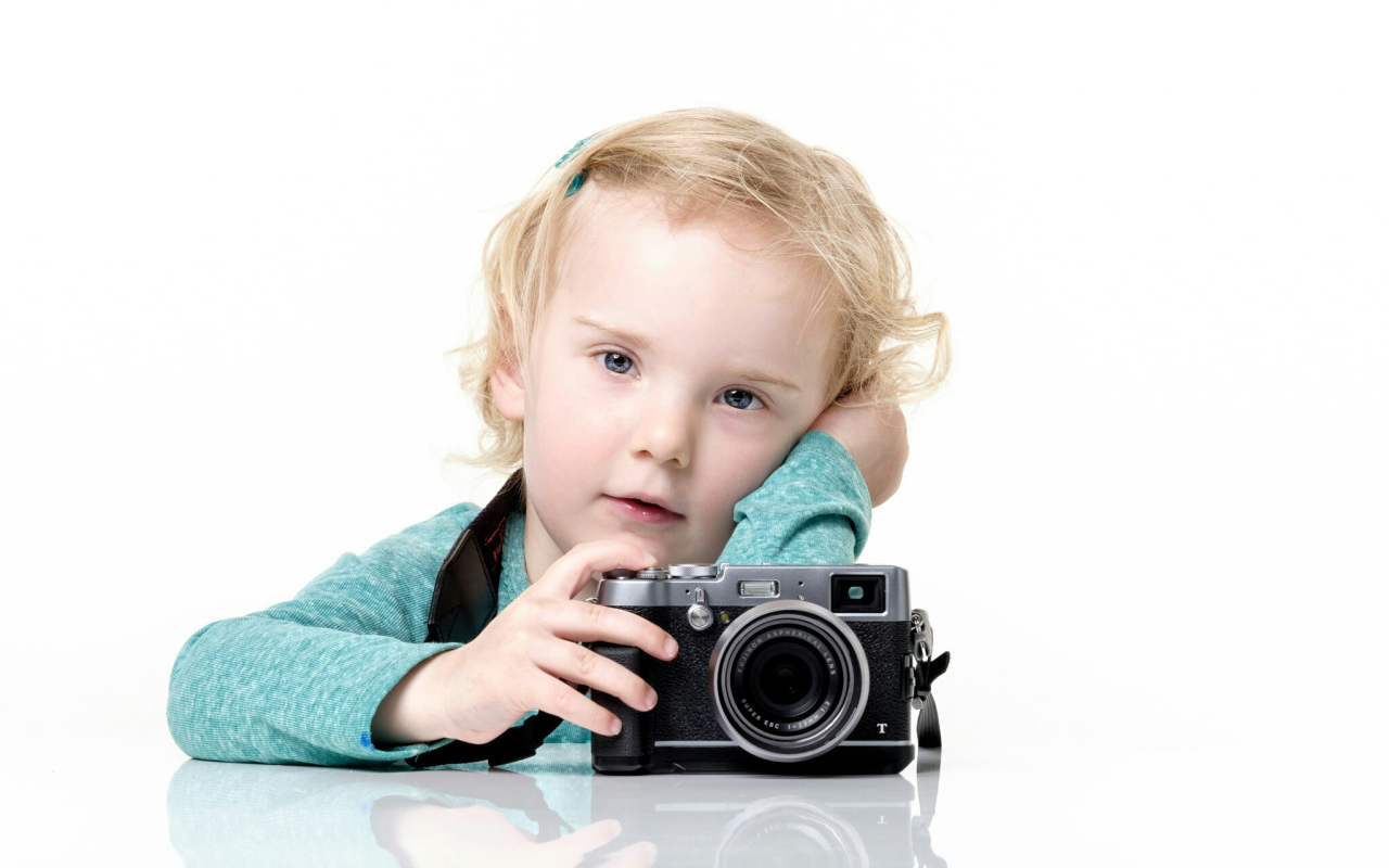 Маленькая девочка с фотоаппаратом на белом фоне