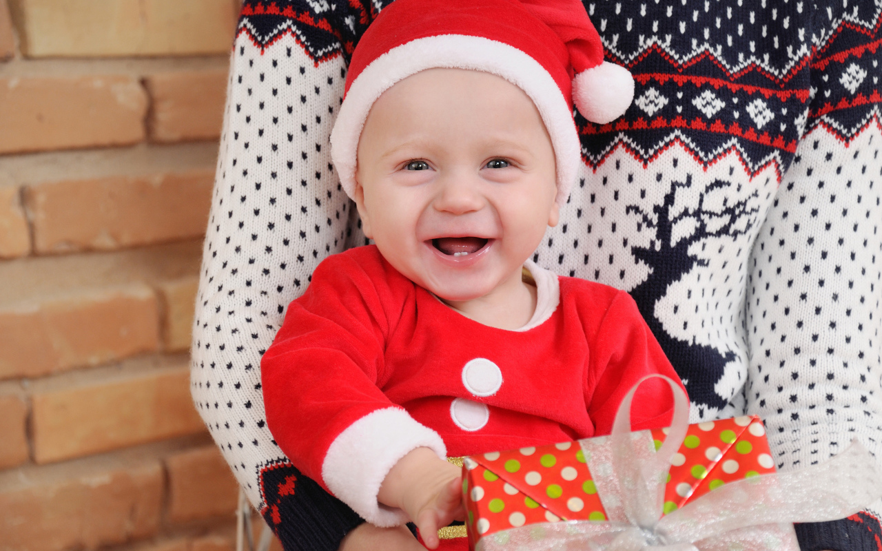 Улыбающийся малыш в костюме с подарком на руках 