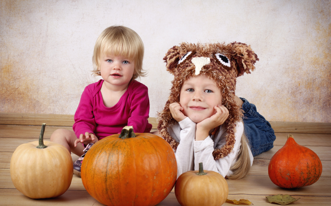 Два маленьких ребенка с тыквами в комнате