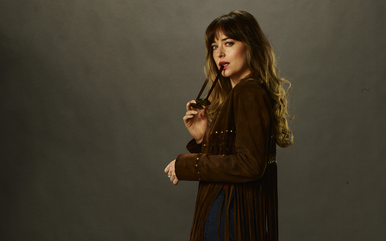 Актриса Дакота Джонсон с очками в руке на сером фоне