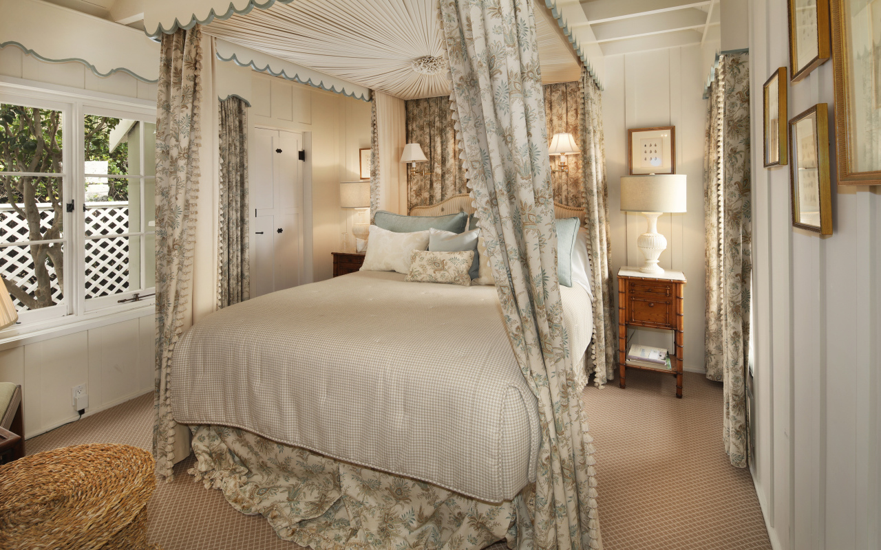 Высокая кровать с занавесками в спальной комнате в пастельных тонах 